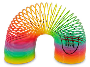 Plastic spring toy, known as a Slinky, displayed in an arched position. The coils transition through a rainbow gradient of colours